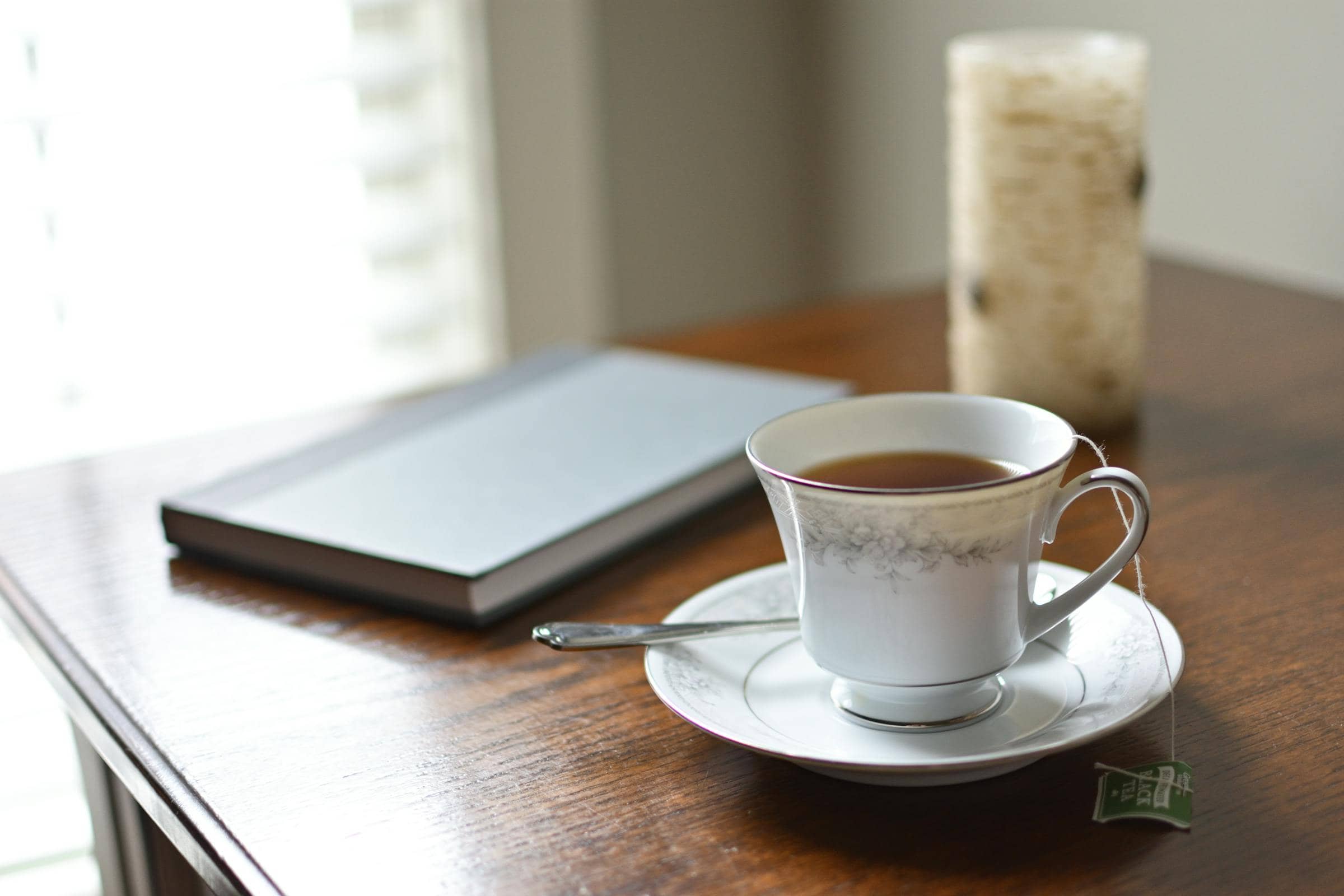 An open journal, a porcelain teacup and a single birch candle on a slow afternoon table — the practice of reflection.